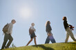© AnnaStills - Low angle shot of secondary school students with books, backpacks and robots in hands walking on fresh cut grass