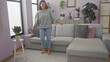 © Krakenimages.com - A joyful woman dances casually in a modern living room, reflecting a cozy, relaxed home atmosphere.