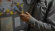 © Krakenimages.com - Man in detective's office analyzing evidence board with smartphone, evidencing investigation focus.