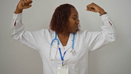 Confident black female doctor poses flexing arms with stethoscope isolated on white background