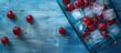 © Ilgun - Blue wooden textured background with a red sweet cherry filled ice cube tray featuring copy space image