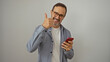 © Krakenimages.com - Mature hispanic man smiling while giving a thumbs up and using a mobile phone isolated against a white background