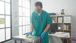 © Krakenimages.com - Hispanic male doctor cleaning in a bright hospital room wearing scrubs and gloves