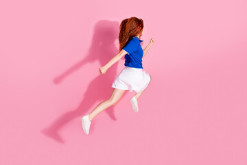 Wall Mural - Full length photo of adorable lovely girl wear short skirt jumping high running empty space isolated pink color background