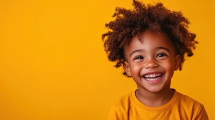 A joyful young child with curly hair beams a wide smile, wearing a yellow shirt against a vibrant yellow background, capturing pure happiness and innocence.