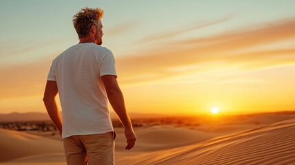 A man stands in vast sand dunes during the serene hour of sunset, captivated by the beauty of the landscape and the tranquility enveloping the environment.