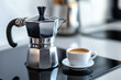 © SnapVault - A close-up of a classic Italian coffee maker brewing fresh espresso on a sleek, modern stovetop, accompanied by a white coffee cup, capturing the elegance and simplicity of morning coffee rituals.