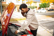 © Paula - Man inspecting car engine while on phone