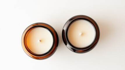 Poster - Two unlit white hand poured soy wax scented candles in brown glass jars isolated for use in cozy or holiday themed designs as well as self care concepts viewed from above