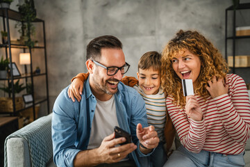 mum, dad and son have online shopping on mobile phone with credit card