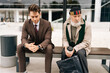 © dikushin - Portrait of communication young businessman and old homeless man sitting on bench, representing growing gap between rich and poor in modern society. Concept of social issues and economic disparity.