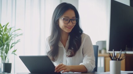 Poster - A woman is sitting at a desk with a laptop and a tablet