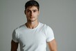 © Suriyo - A handsome man in a white T-shirt strikes a pose under bright studio lighting, with a smooth gray background.