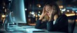 © Chayan - A stressed woman sits at a computer, holding her head in frustration, with a dimly lit office environment in the background.