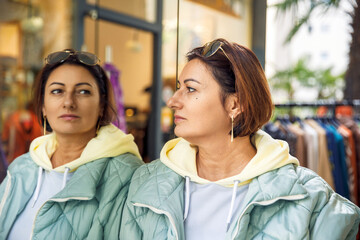 Woman in reflective moment near clothing store