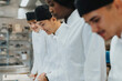 © Maskot - Smiling male and female trainee chefs practicing in culinary school