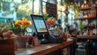 © Gita - charming cafe counter featuring a digital POS system, fresh flowers, and fruits. The backdrop highlights a bright and inviting atmosphere with shelves and greenery.