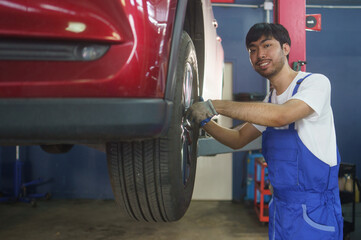 Asian mechanic worker checking at car tyre rubber condition needed for replacement. after service at auto repair shop concept