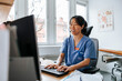 © Maskot - Happy female medical expert wearing headset and doing online consultation on video call through computer at clinic
