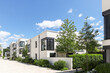 © ah_fotobox - Residential area with ecological and sustainable green residential buildings, low-energy detached houses with white facade and flat roof, timber construction and green courtyard
