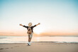 © Davide Angelini - Happy man with backpack standing with arms up at the beach - Delightful tourist enjoying summer vacation by the seaside - Traveling life style and well being concept