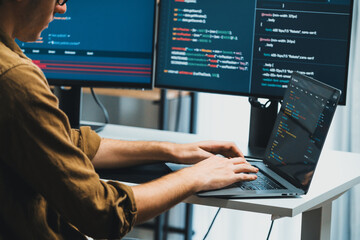 IT developer working online software development on pc monitors at modern home office on coding application screens, creating updated latest program firmware information version concept. Gusher.