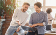 © Prostock-studio - Two young men colleagues sharing creative ideas at workplace, looking at laptop screen, casual office atmosphere