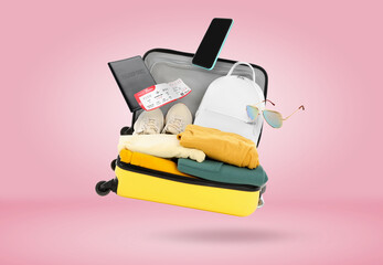 Sticker - Suitcase, clothes and other items in air on pink background. Ready to travel