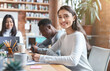 © Prostock-studio - Close up of positive mixed race young woman attending business meeting in office, sitting with international colleagues around table