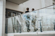 © Maskot - Full length of male and female colleagues walking by glass railing at lobby