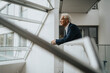 © Maskot - Senior businessman with white hair leaning on railing