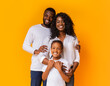 © Prostock-studio - Happy Family Of Three Hugging Posing Over Yellow Background In Studio