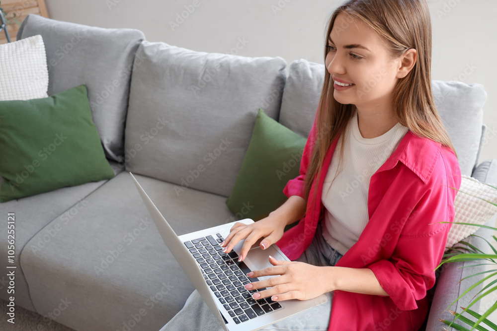 Smiling young woman using laptop on sofa at home