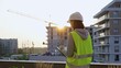 © volha_r - Construction female engineer taking notes and writing on clipboard while inspecting a building site at sunset. Industry development concept