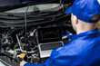 © zphoto83 - A mechanic analyzes engine data on a laptop during a vehicle inspection under the hood in a garage setting
