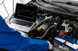 © zphoto83 - An automotive technician analyzes data using a laptop while inspecting an engine in a workshop during the day