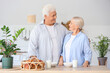 © Pixel-Shot - Happy senior couple with glasses of milk and tasty buns in kitchen