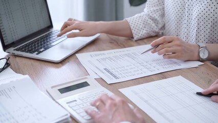 Professional female bookkeeper or auditor are working on business finances with a colleague, using calculator and laptop. Finance audit and taxes