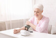 © Prostock-studio - Everyday health check-up. Senior lady with hypertension measuring blood pressure herself at home, empty space
