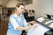© JackF - Woman employee of printing house puts a sheet of paper into a plotter