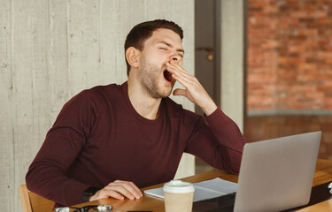 Poster - Sleepy Office Guy Yawning At Laptop Sitting At Workplace Indoor. Work Exhaustion. Selective Focus
