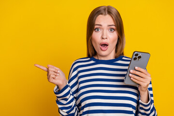 Photo of shocked cute woman wear striped stylish clothes presenting empty space isolated on yellow color background