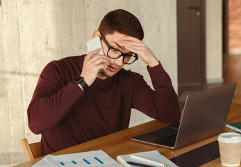 Poster - Tired Manager Guy Talking On Cellphone Working Sitting At Laptop In Modern Office. Selective Focus