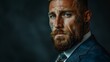 © ifoto - A handsome, muscular man with a beard and tattoos wearing a suit and looking serious in a professional photography style