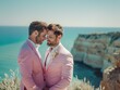 © Natalia - Two grooms in pink suits embrace on a cliff overlooking the ocean. AI.