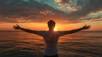 Young man arms outstretched by the sea at sunrise enjoying freedom and life, people travel wellbeing concept. 