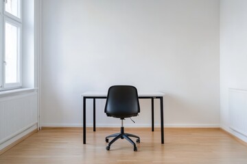 Poster - A black office chair sits in front of a white desk in a room with a white wall. The chair is empty and the desk is bare, giving the room a minimalist and clean appearance