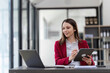 © wichayada - Business Woman Working on a Desk with Laptop and Tablet in Modern Office Environment