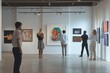 © Krisartist94 - Visitors admire contemporary art at a spacious gallery during a sunny afternoon, engaging with various vibrant artworks on display
