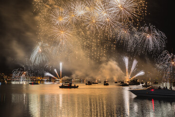 fireworks at night over lake with boats. ponte tresa and lake lugano with a fireworks display, north